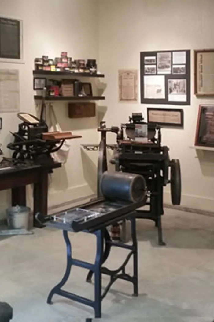 Vintage printing press and office equipment in a historical display.